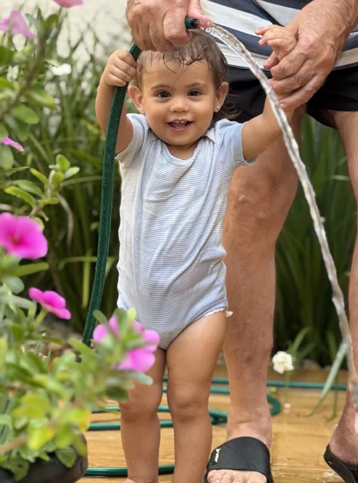 Lara se divertindo com a mangueira no jardim florido