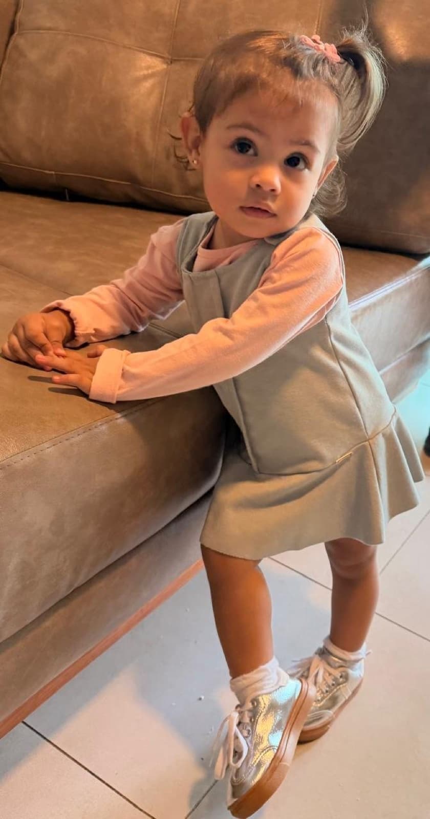 Lara de vestidinho verde apoiada no sofá