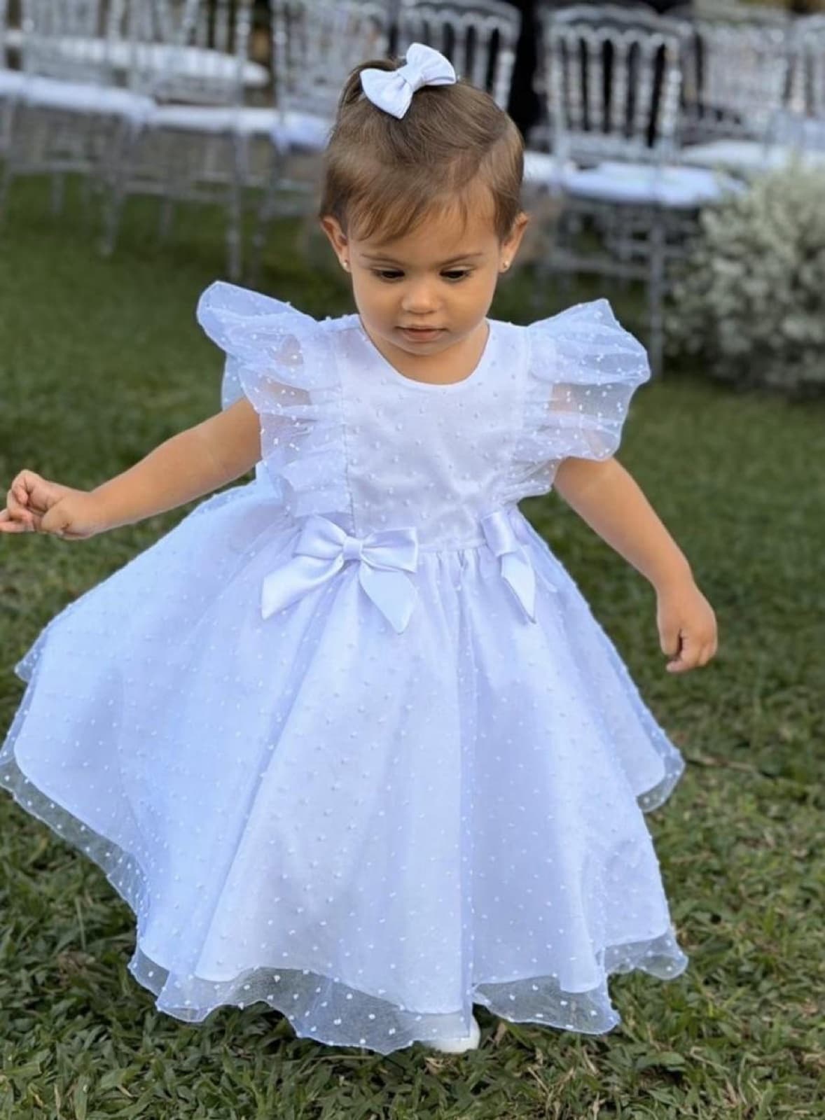 Lara de vestido branco de tule brincando na grama